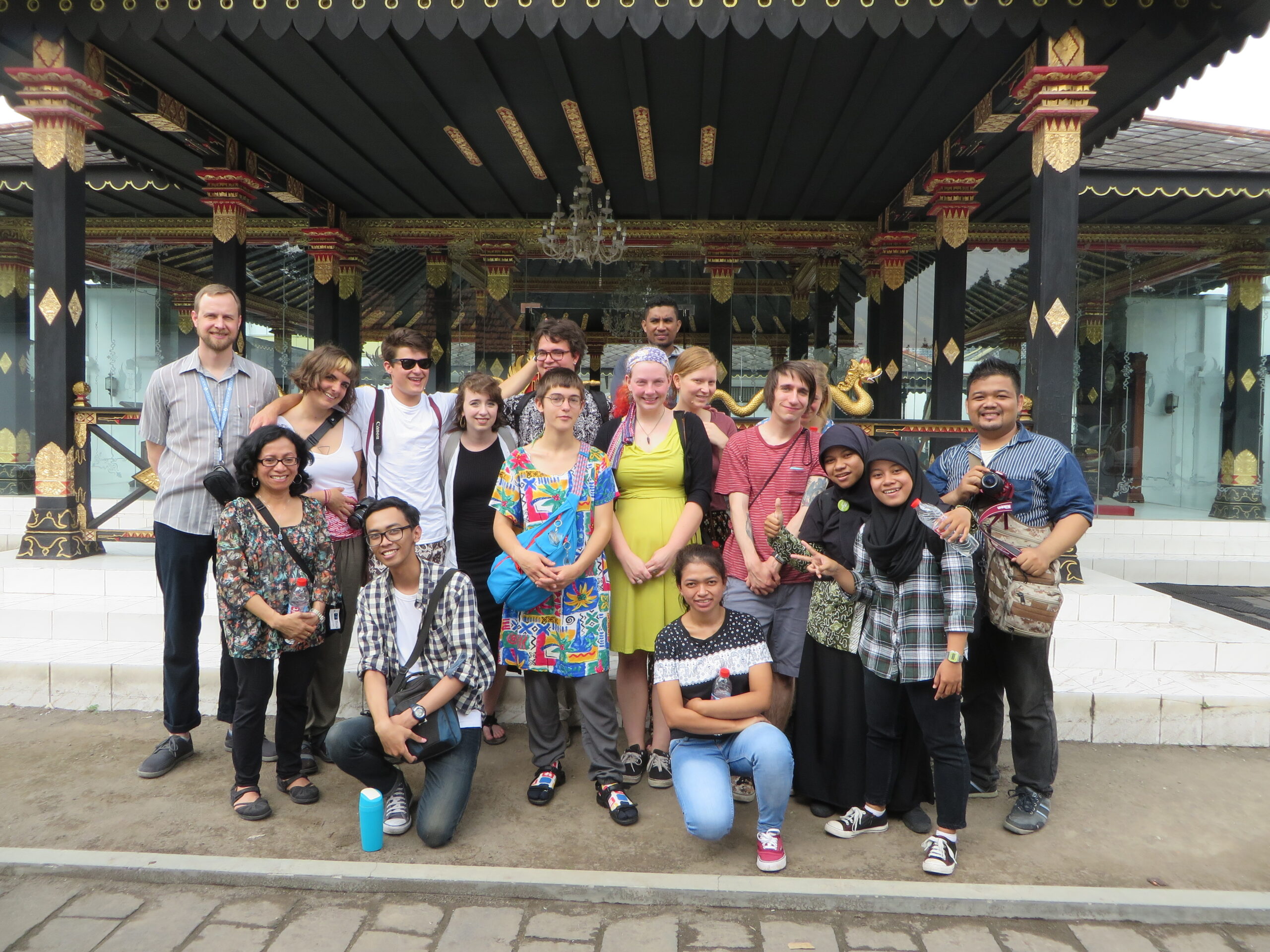 Students and professors gather in front of the camera for a group photo at a temple.