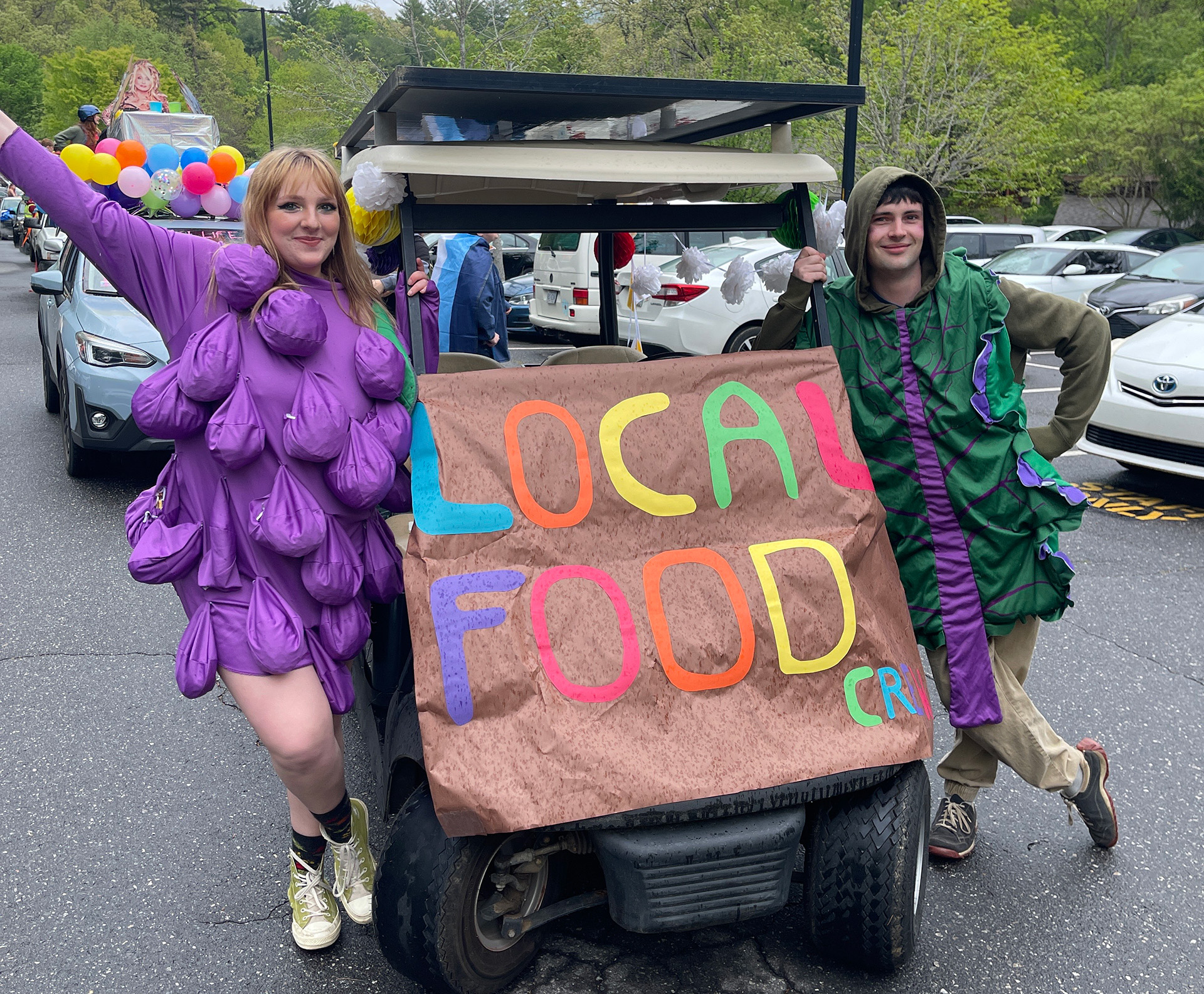 Local foods crew students pose in their fruit costumes beside their decorated golfcart for the Big Gay Earth Day Parade