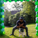 Public saftey officer John poses under the balloon arch with an inflatable cow