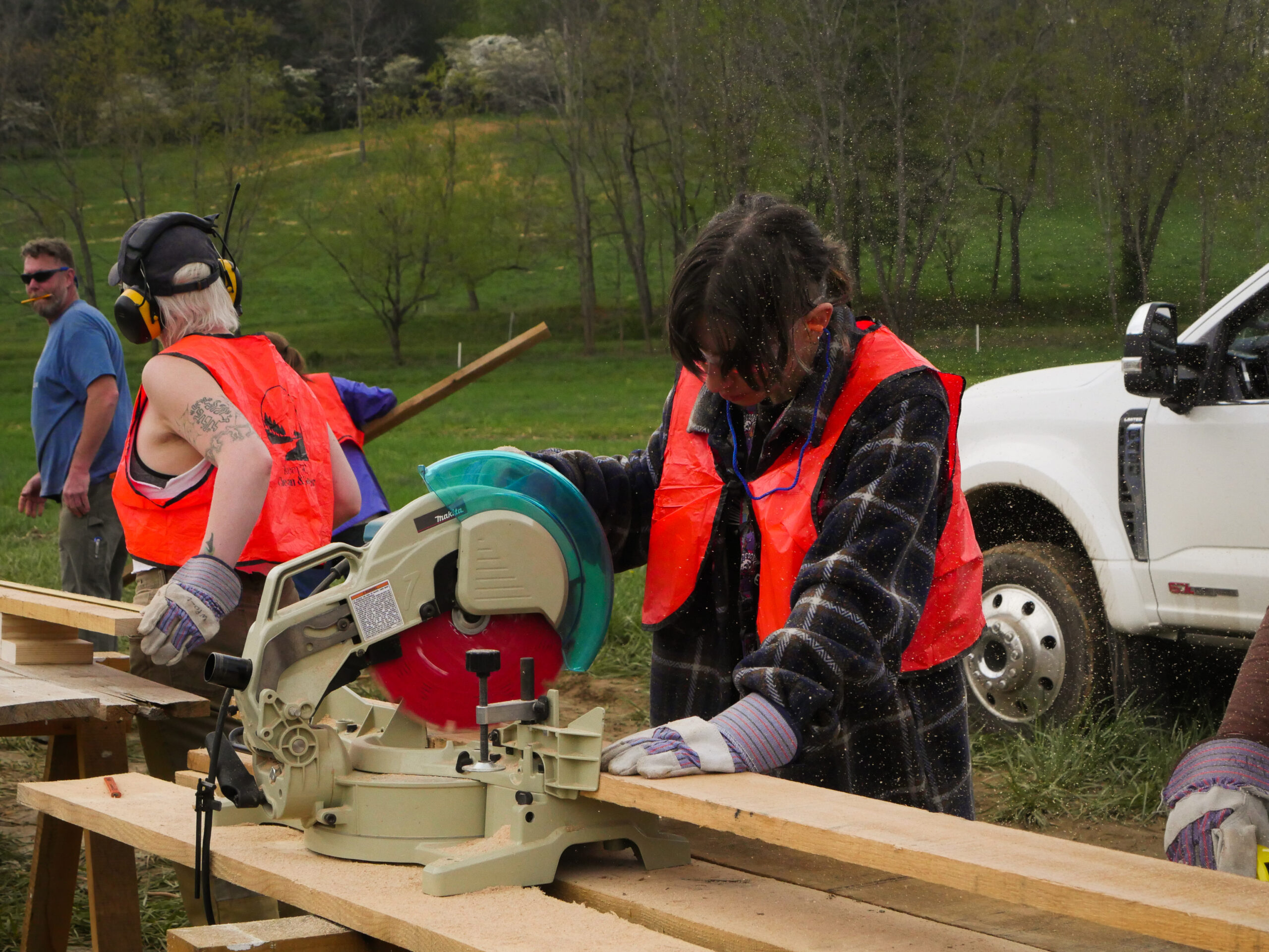 A student on workday using a table saw to cut planks for the farm fence.