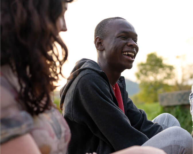 An international student sits smiling with their peers.
