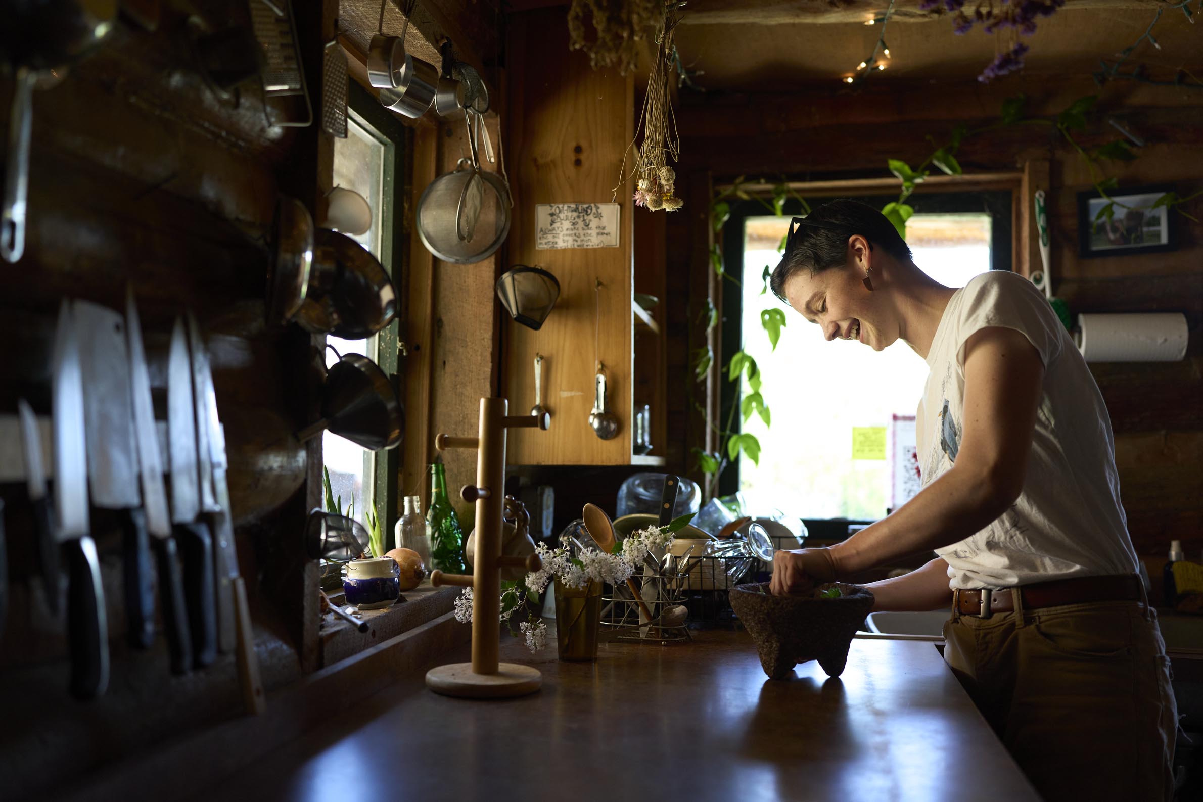 A Herb Crew student uses a mortar and pestle to grind some herbs in the herb cabin.