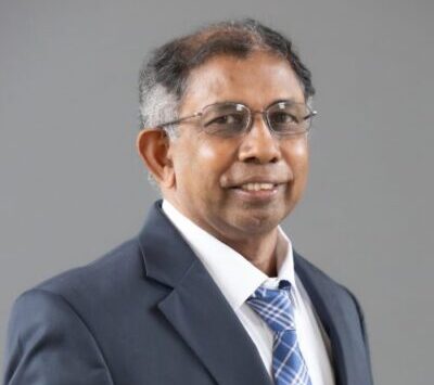 Professor Muthukrishnan stands and smiles for a headshot photo.