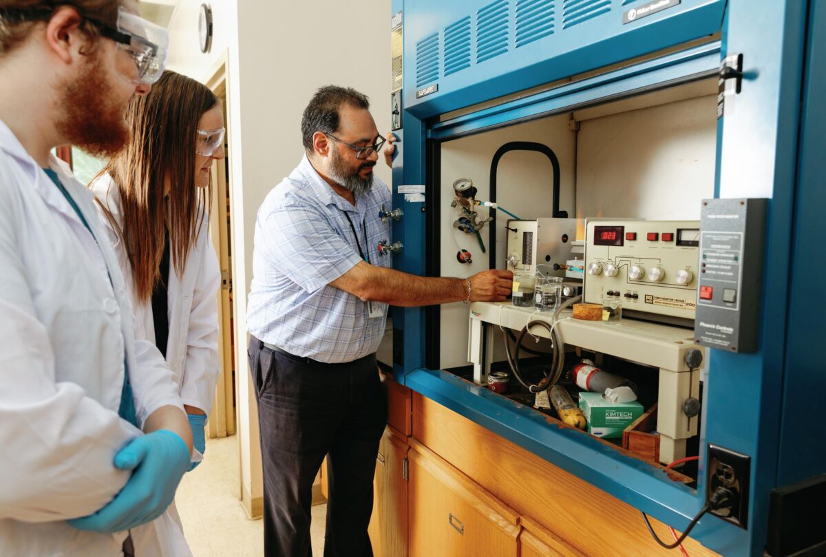 Students watch closely as their professor explains chemistry equipment in the lab.