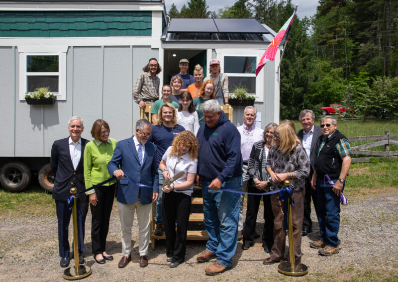 Student Maeve Williams cutting the ribbon at the Tiny Home dedication ceremony