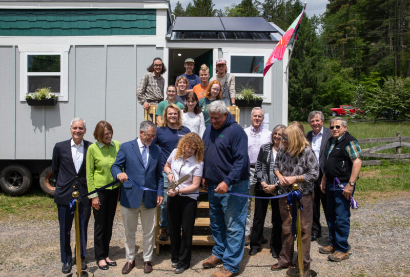 Student Maeve Williams cutting the ribbon at the Tiny Home dedication ceremony