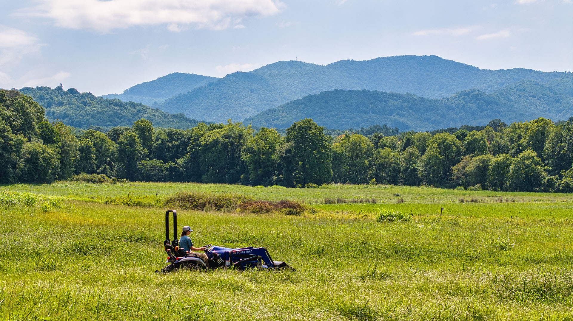 A student drives a soltrac tractor across the Warren Wilson College Farm outside of Asheville, North Carolina.