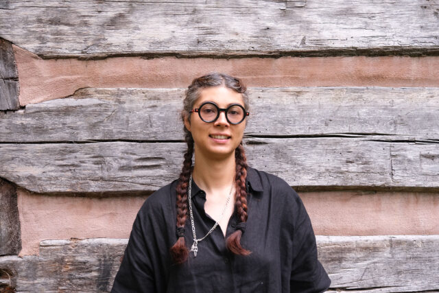 WWC Faculty Member Cris Culton stands in front of a wood backdrop.