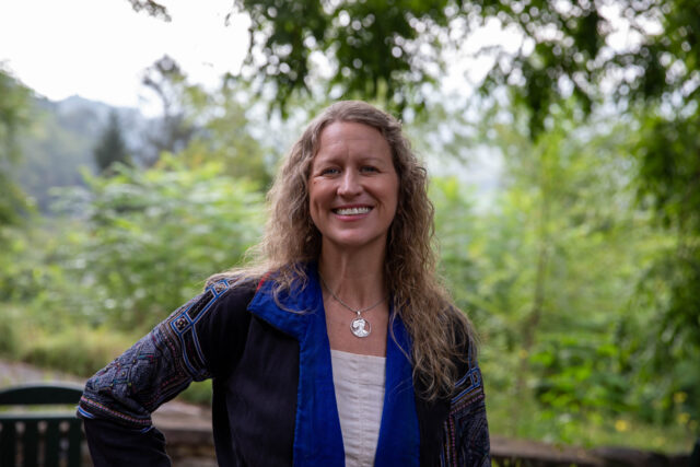 Visiting Professor Hayley Joyell stands smiling with the background of the mountains.