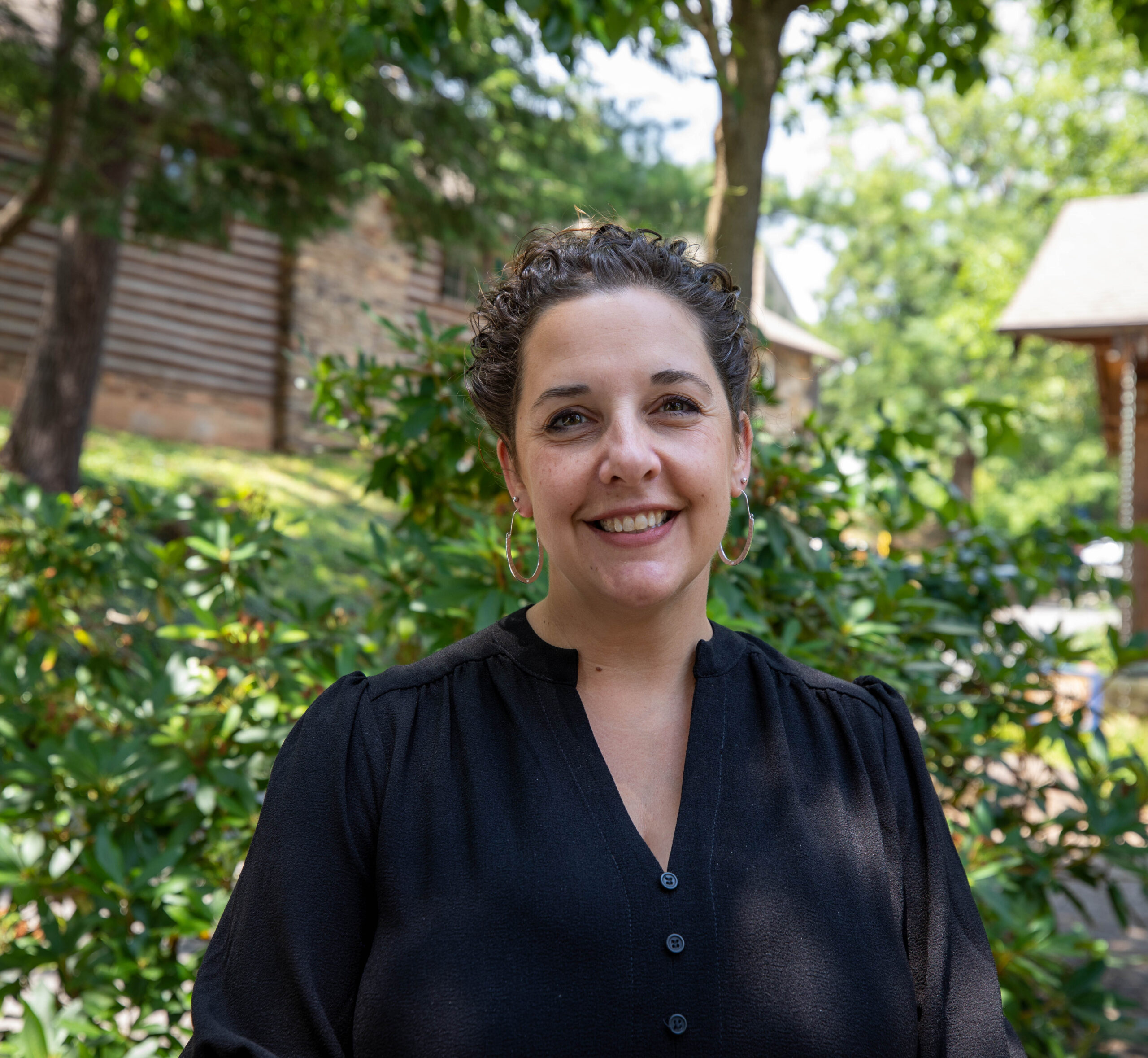 Vice President for Institutional Advancement, Marketing and Strategic Communications stands in front of Orr Cottage smiling.