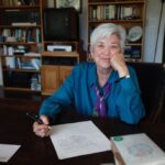 Ellen Bryant Voigt, creator of warren wilson college's Master of fine arts program for writers, sits at a table, pen in hand, writing.