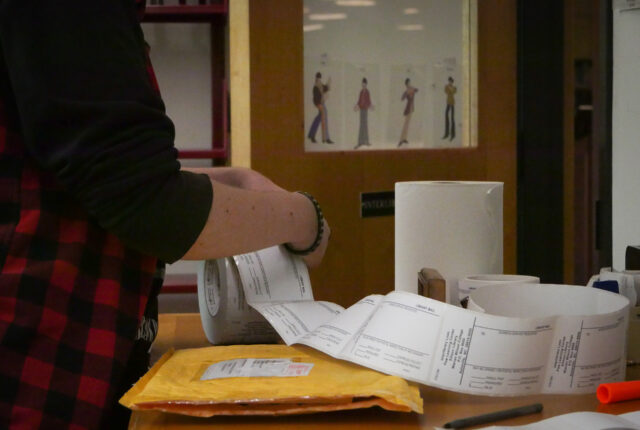 A student on the library circulation crew stickers interlibrary loan packages.