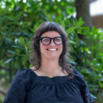 Director of the Library, Julia Haverstock stands and smiles in front of the admissions building at Warren Wilson College.