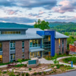 An aerial photo of Myron Boon Hall. A beautiful mountain vista can be seen in the background