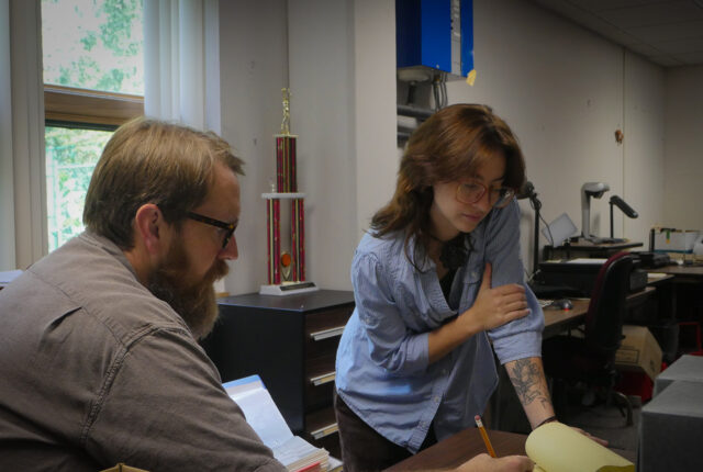 Dr. Jeff Keith works with a library archives student.