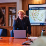 Dr. Keith McDade, Director of the Master of Science in Applied Climate Studies program looks up from his computer and smiles at a group of students.