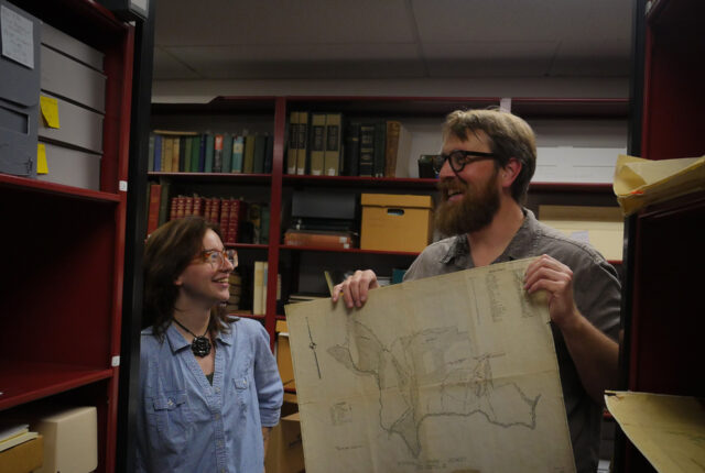 Dr. Jeff Keith works with a library archives student.
