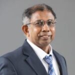 Professor Muthukrishnan stands and smiles for a headshot photo.