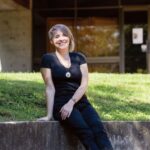alumni ashley rogers sits in the outdoor amphitheater and poses for a picture