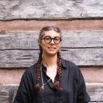 WWC Faculty Member Cris Culton stands in front of a wood backdrop.