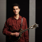Korey Brodsky stands with his mandolin and poses for a picture