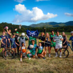 A group of Warren Wilson student athletes stand with their equipment smiling and cheering