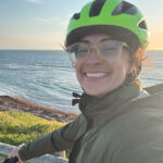 Professor Jenn Kaplan takes a selfie on her bike on the coast.