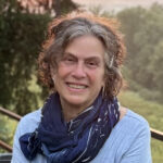 Emeritus art professor Leah Leitson smiles in an outdoor setting.