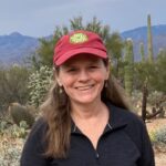 Dr. Amy Boyd stands and smiles for a picture in front of a backdrop of the mountains.