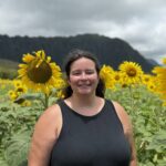 Dr. Hannah Pearson stands and smiles in a sunflower field.